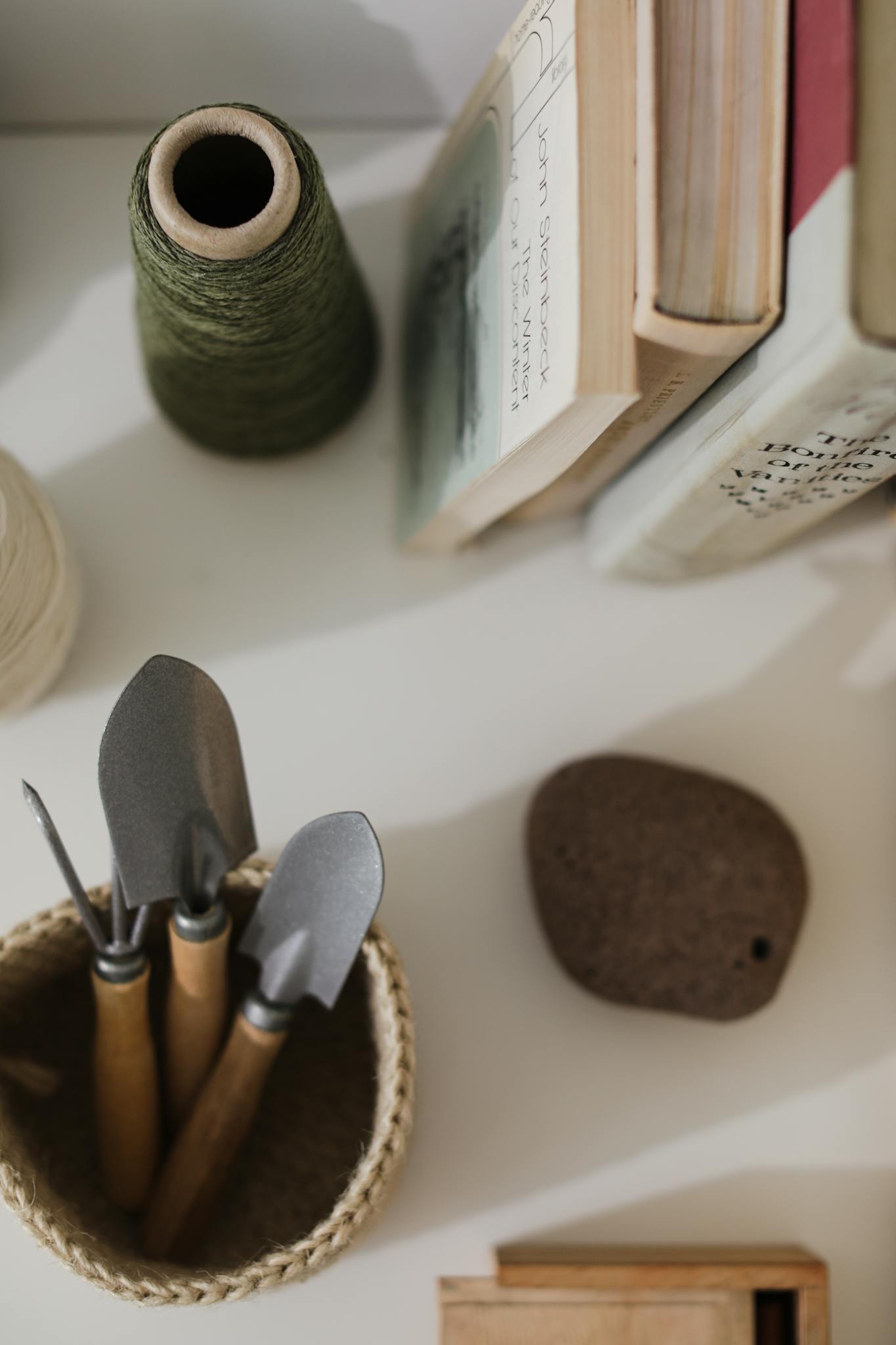 Flat lay of gardening tools, books, and thread on a desk.